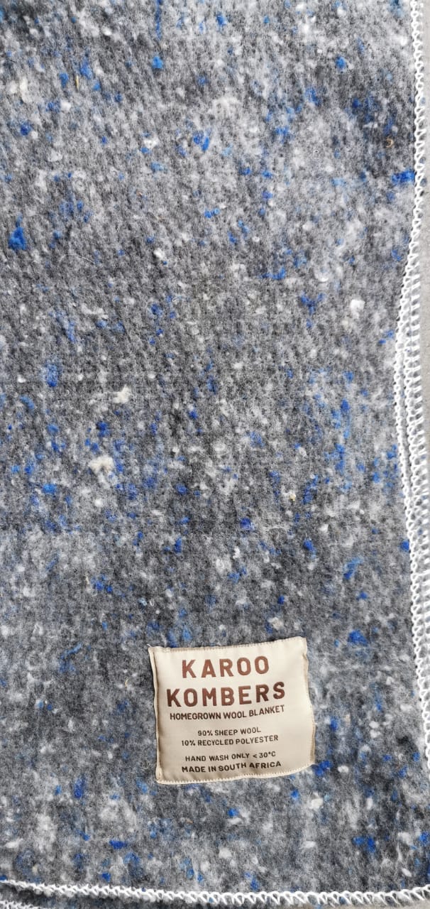 Close-up of a textured fabric with a visible label on a gray and blue speckled background