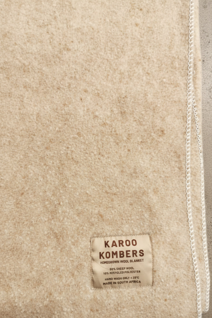 Textile with a 'Karoo Kombers' label on a textured fabric background